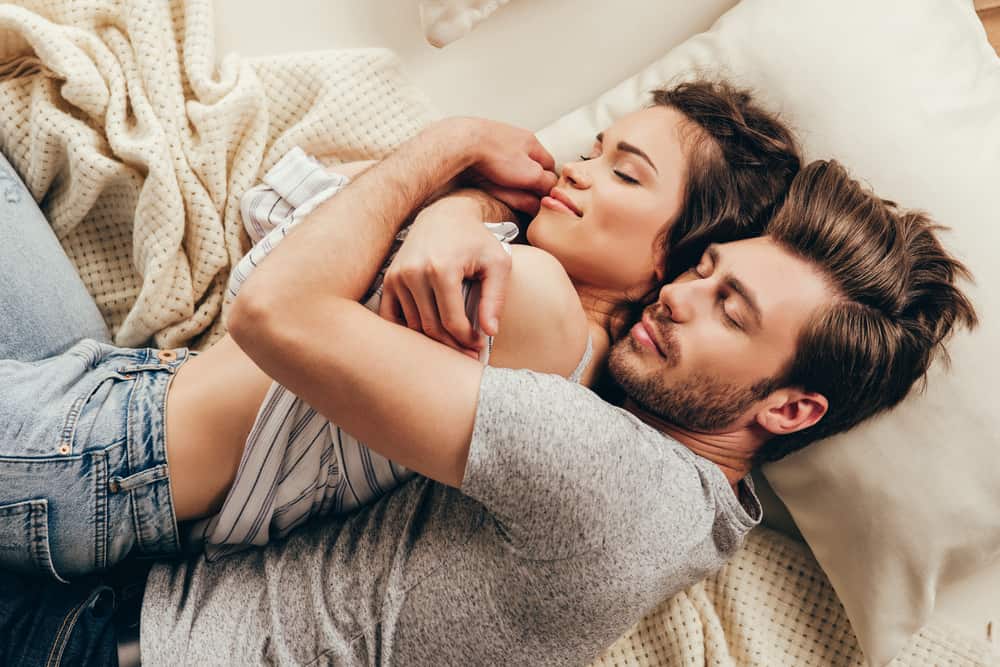 lyckligt ungt par som kramar medan du sover på sängen