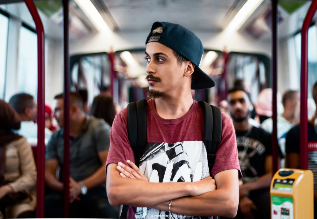 man i baseballmössa som står ensam i kollektivtrafiken