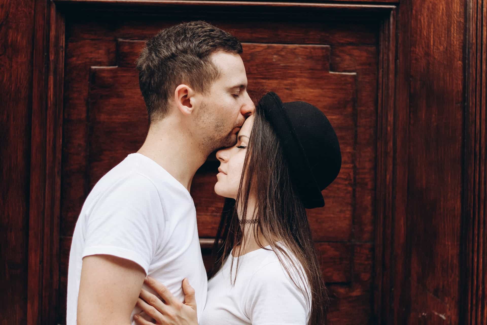 man kysser kvinna med hatt