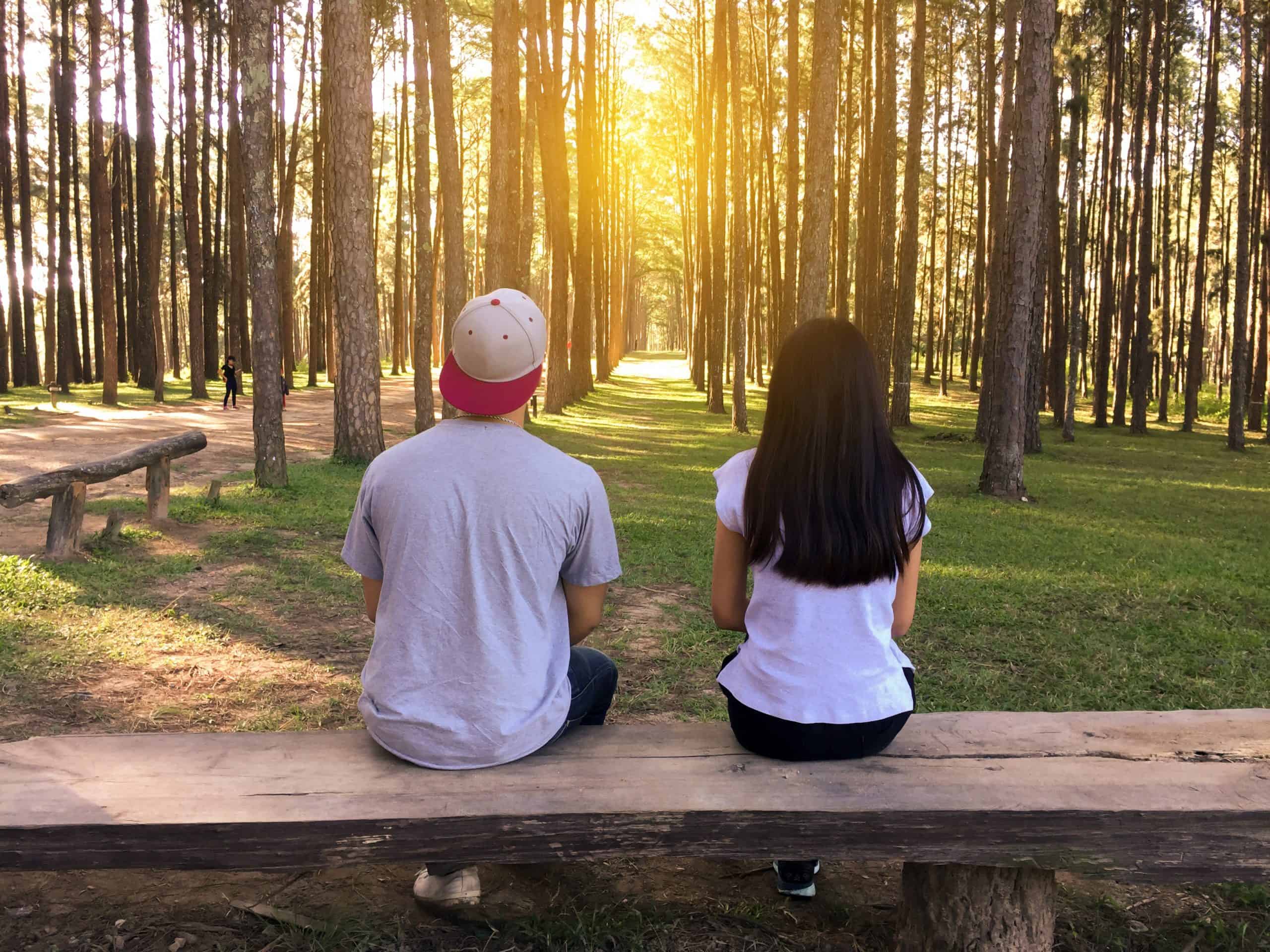 man och kvinna sitter på bänken i skogen
