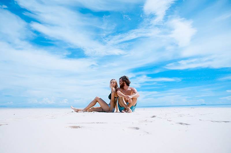 man och kvinna som sitter på stranden under dagtid