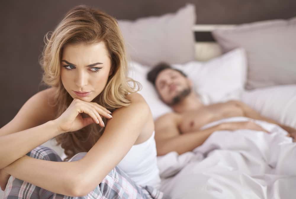 orolig kvinna som tänker medan mannen sover