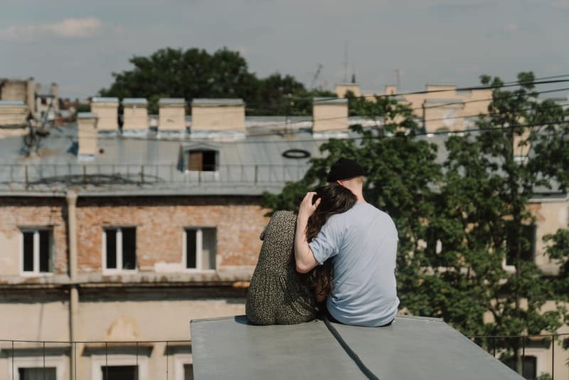 på taket av byggnaden sitter ett älskande par i en omfamning