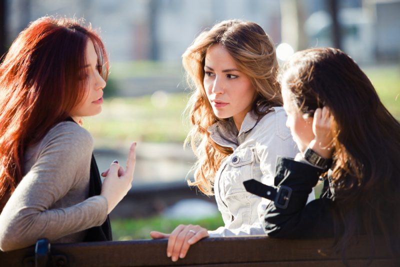 tre kvinnor som sitter i parken och pratar