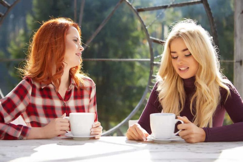 två kvinnor som sitter och dricker kaffe och pratar