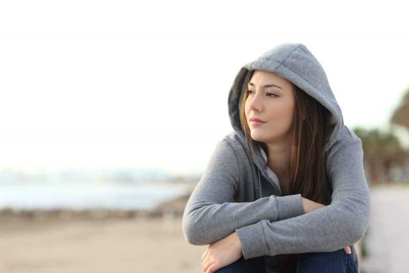 ung kvinna som sitter på stranden ensam