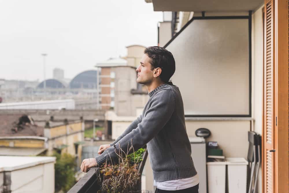 ung stilig man som står på en balkong utomhus