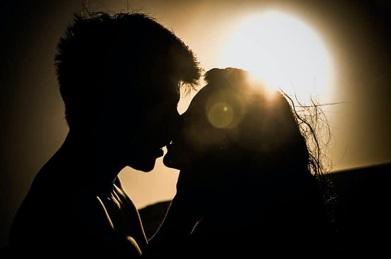 ungt par som kysser i solnedgången