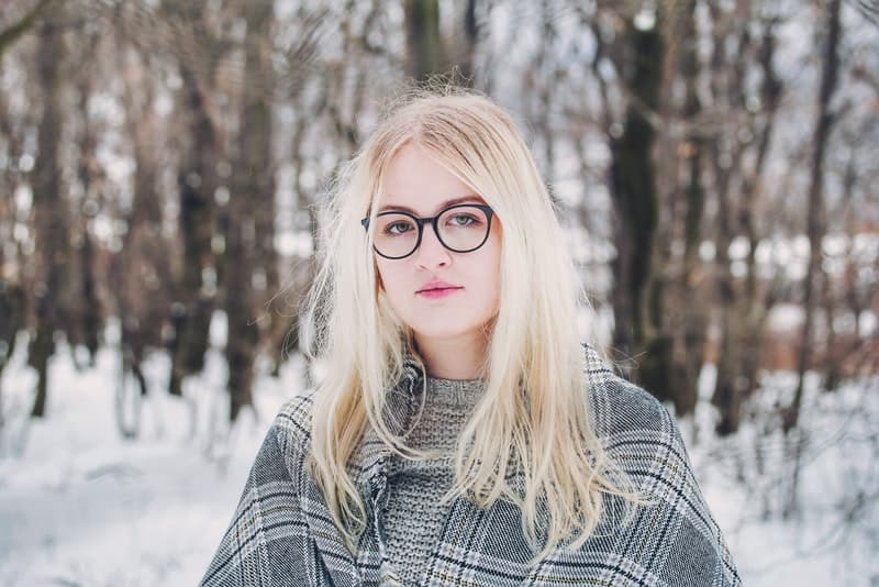 ute i snön står en blondin med glasögon