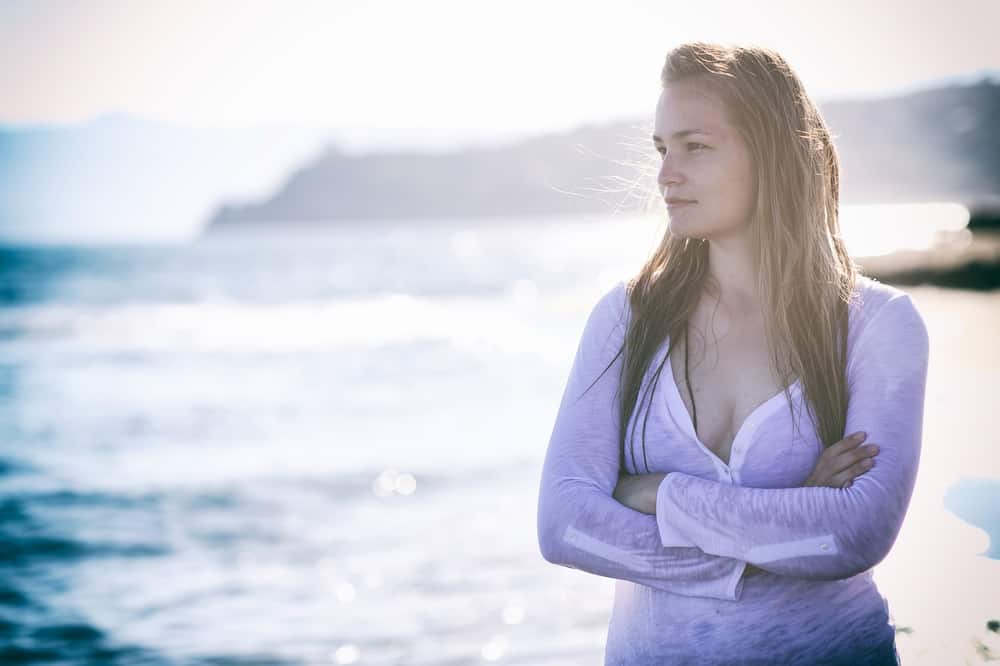 vacker kvinna som står ensam på stranden nära vatten