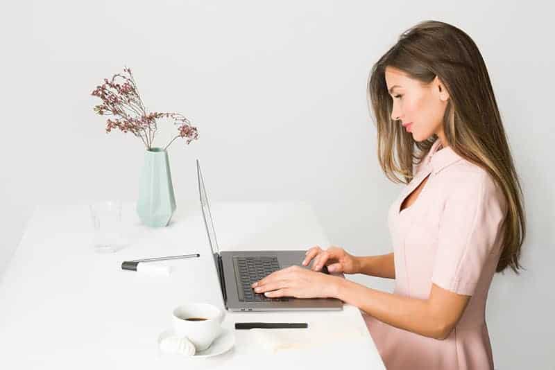 vacker ung kvinna att skriva på bärbar dator