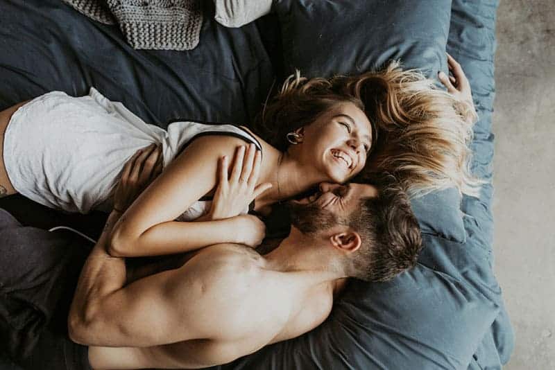 vackra lyckliga par som lägger på sängen