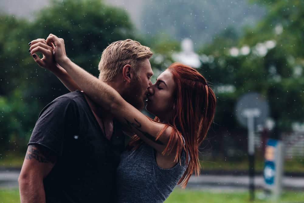vackra par kysser ute i regnet
