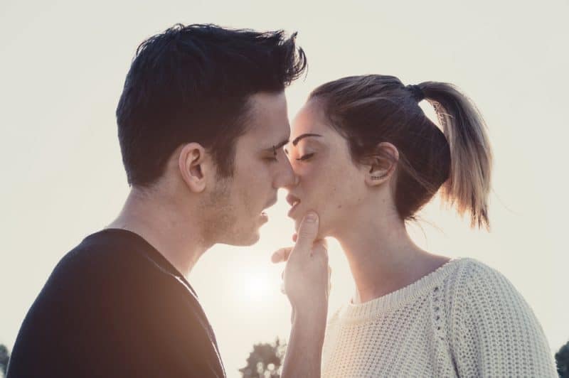 Älska par som utomhus kysser vid solnedgången
