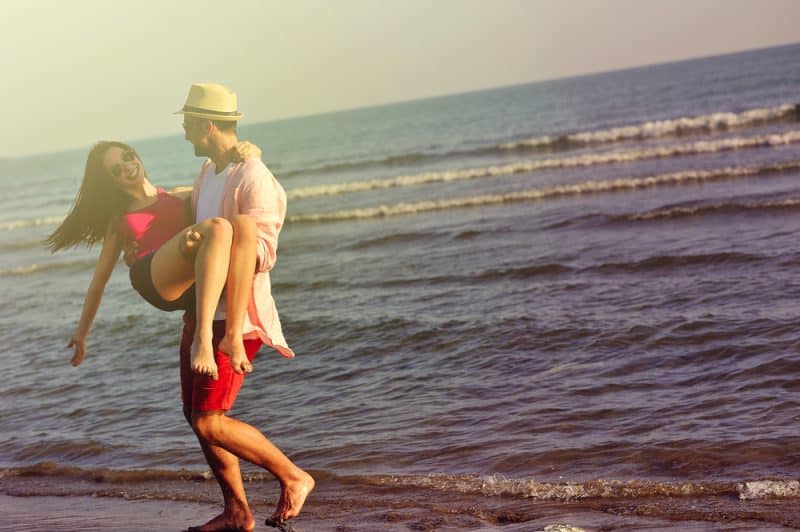 Härligt ungt par som är förälskat som tycker om och har gyckel på stranden