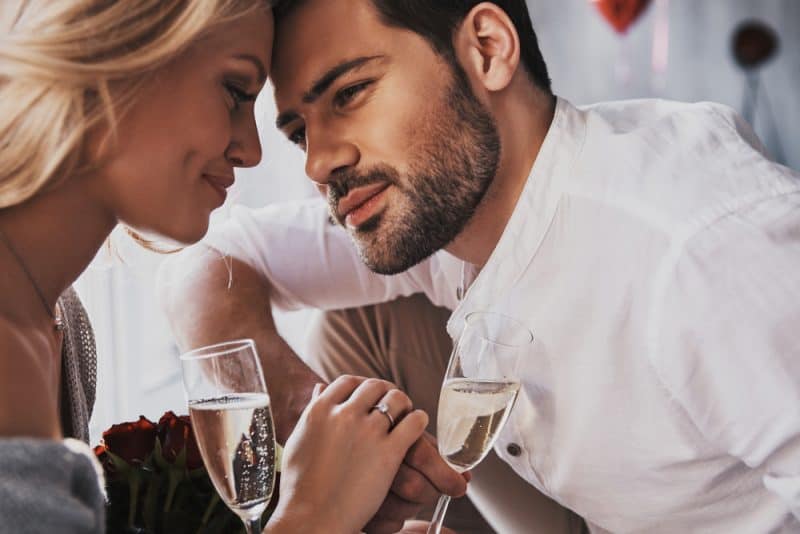 Härligt ungt par som dricker champagne och ler