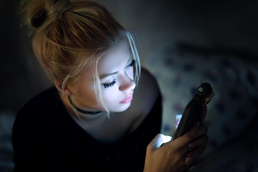 Kvinna som använder smartphonen på säng på natten