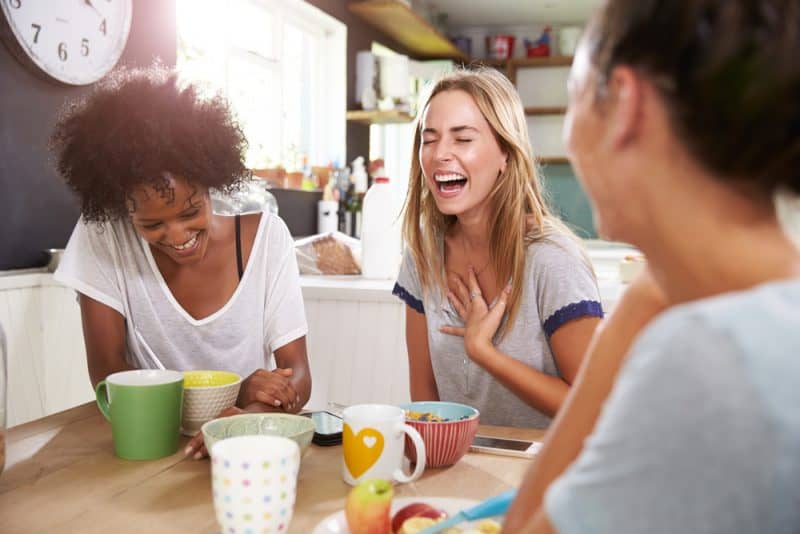 Tre kvinnliga vänner som hemma tycker om frukosten