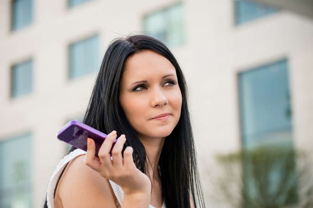Ung härlig kvinna med mobiltelefonen uttråkad från samtal