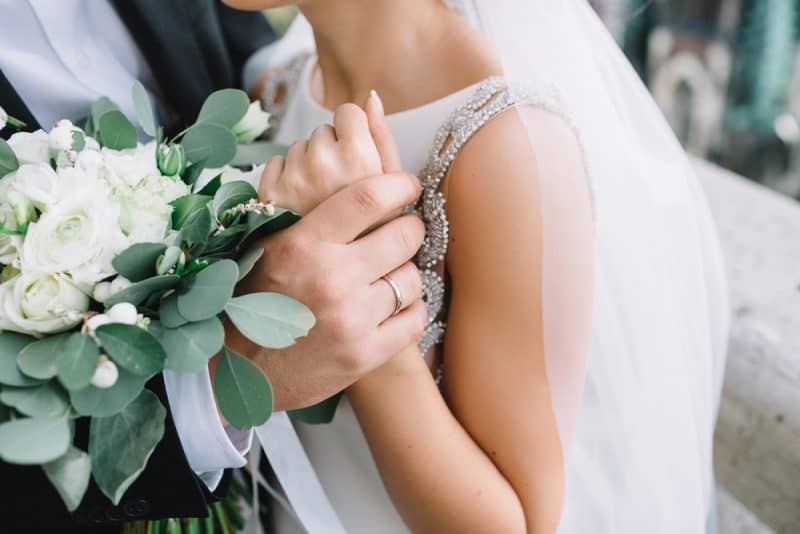 brudgummens hand som håller brudens första anbud