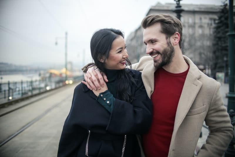 ett leende älskande par som omfamnar går ner på gatan