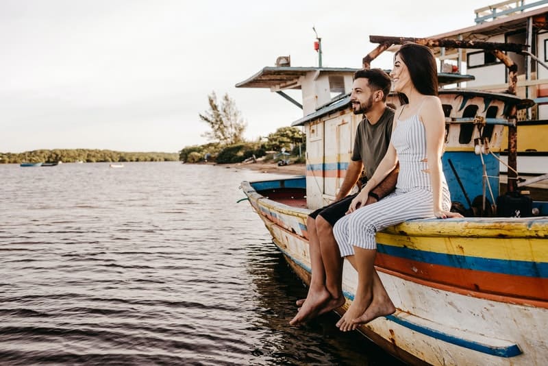 ett leende älskande par som sitter på en båt och tittar på havet