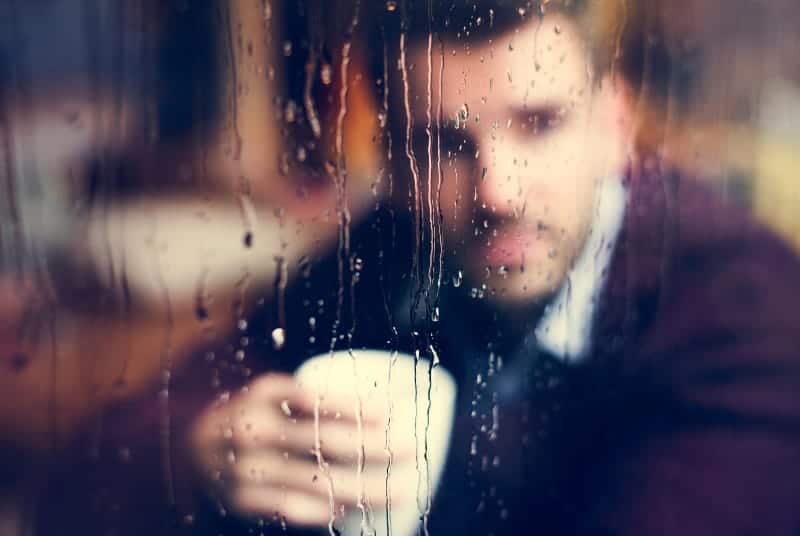foto av mannen genom det våta fönstret i kaféet