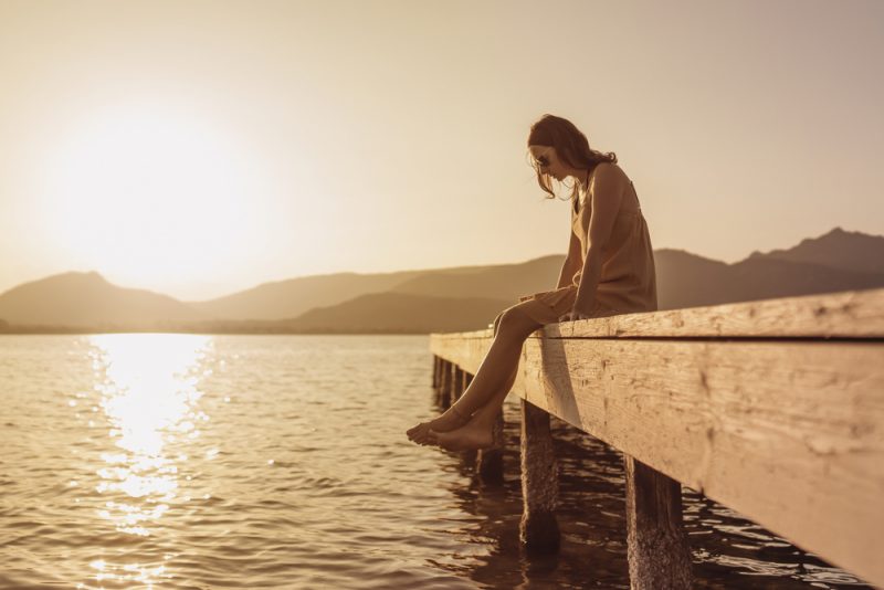 ganska ung kvinna som sitter ensam vid sjön