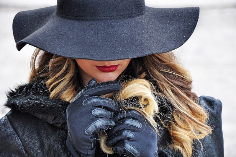 kvinna i svart kappa och svart hatt