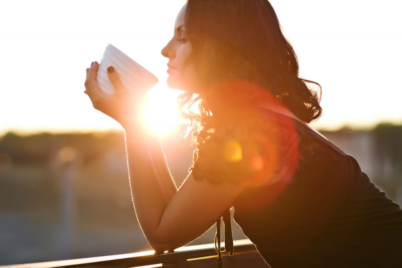 kvinna som dricker kaffe medan man står utomhus