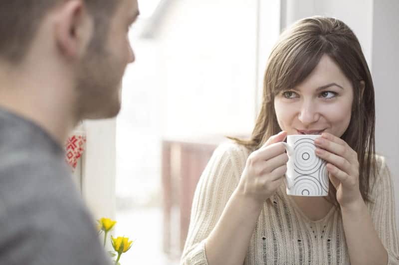 kvinna som flörtar med mannen medan hon dricker kaffe