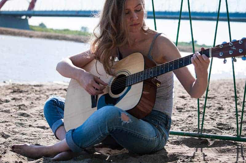 kvinna som spelar gitarr på stranden