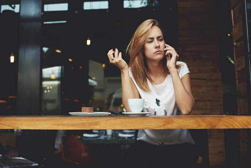kvinnan ser omtänksam ut medan hon pratar i telefon på caféet
