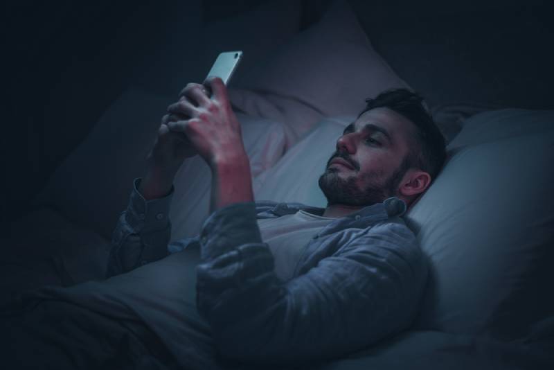 le man med smartphone innan sängen