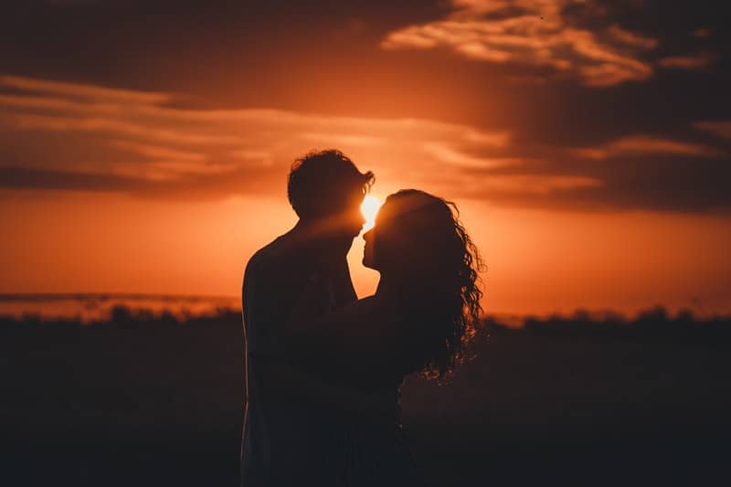 man och kvinna kramar i solnedgången