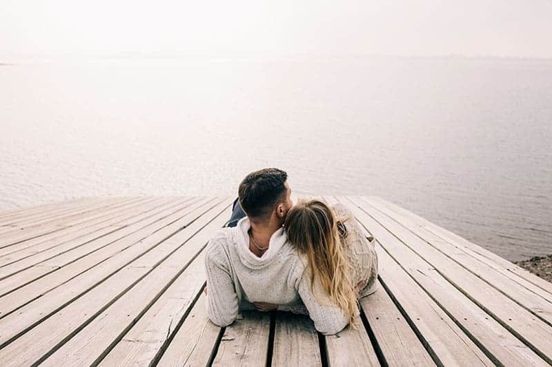 man och kvinna kramar nära sjön