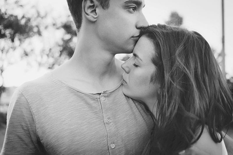 svartvitt foto av man kysser kvinnan i pannan