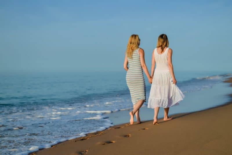 två kvinnor som går på stranden