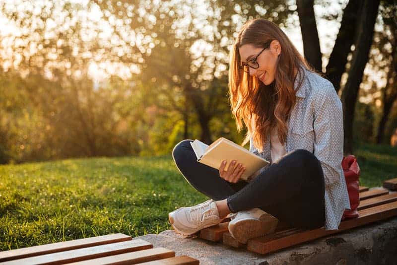 ung kvinna-läser-en-bok-på-bänken