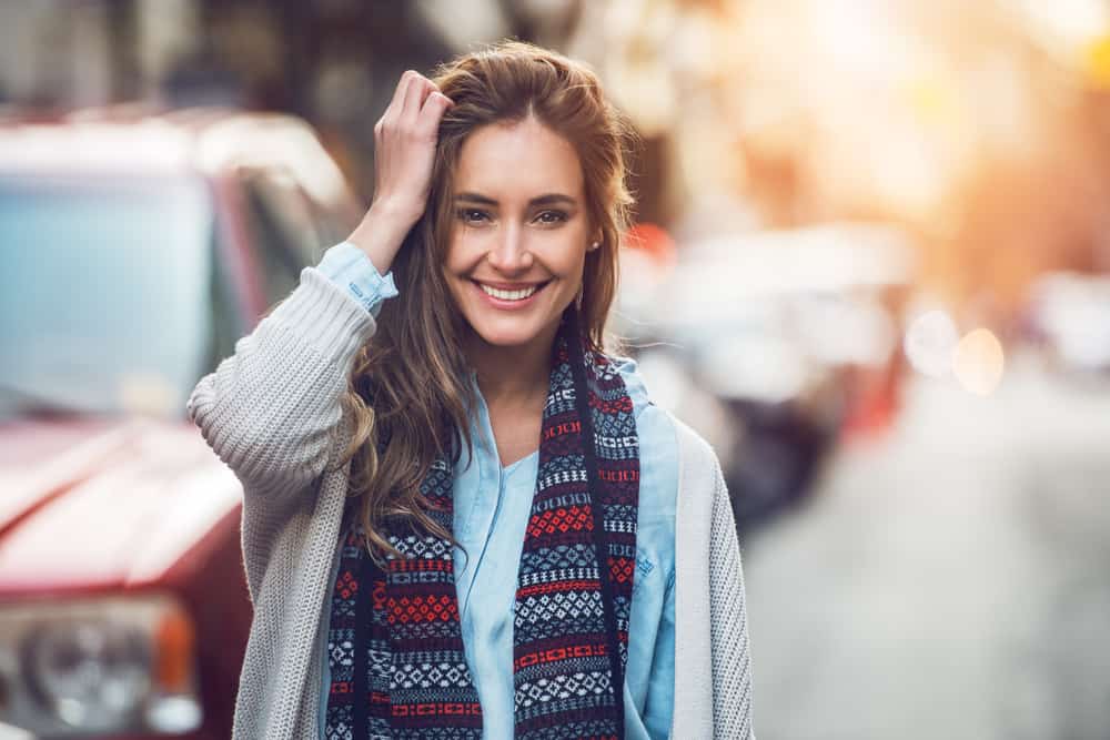 vacker leende kvinna med halsduk som går på gatan