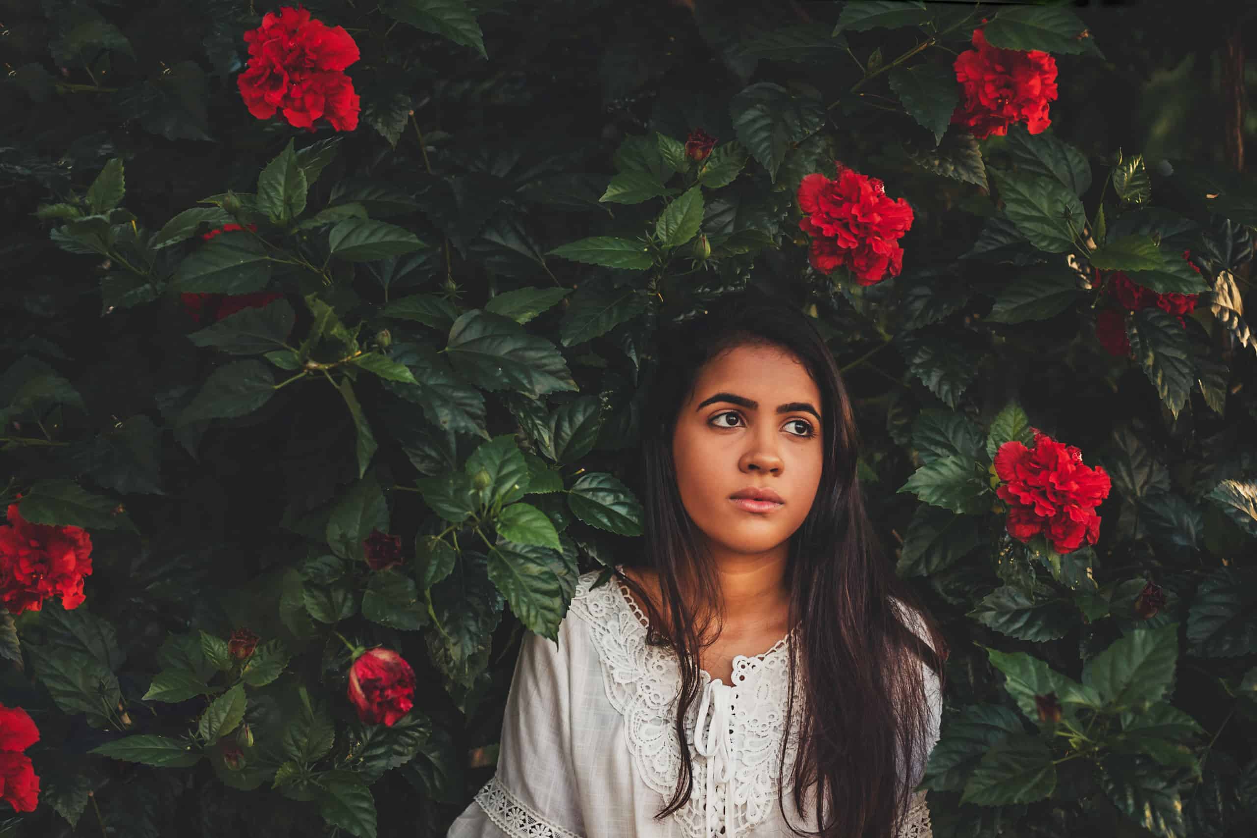 vacker tankeväckande kvinna som står nära blommavägg
