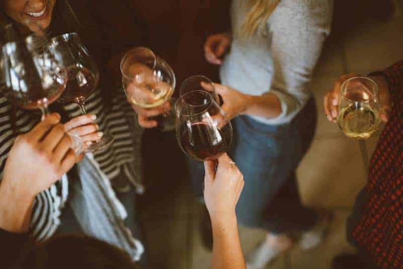 Grupp av vänner som hejar med exponeringsglas av vin