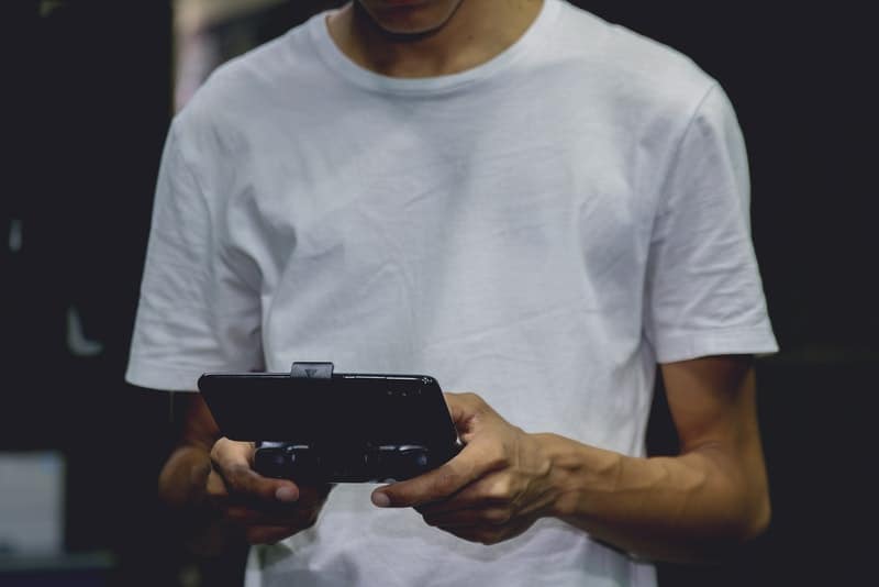en man i en vit T-shirt som spelar ett spel på sin smartphone