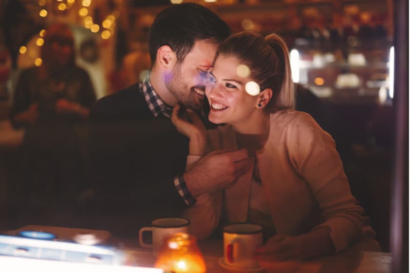 ett leende älskande par som kramar på ett kafé