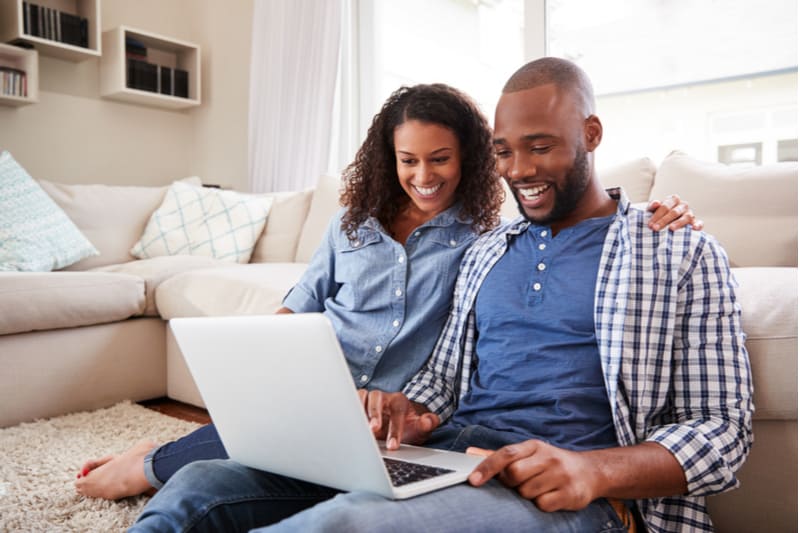 ett leende svart par använder en bärbar dator