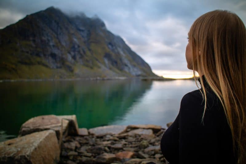 kvinna med blont hår som står framför sjön