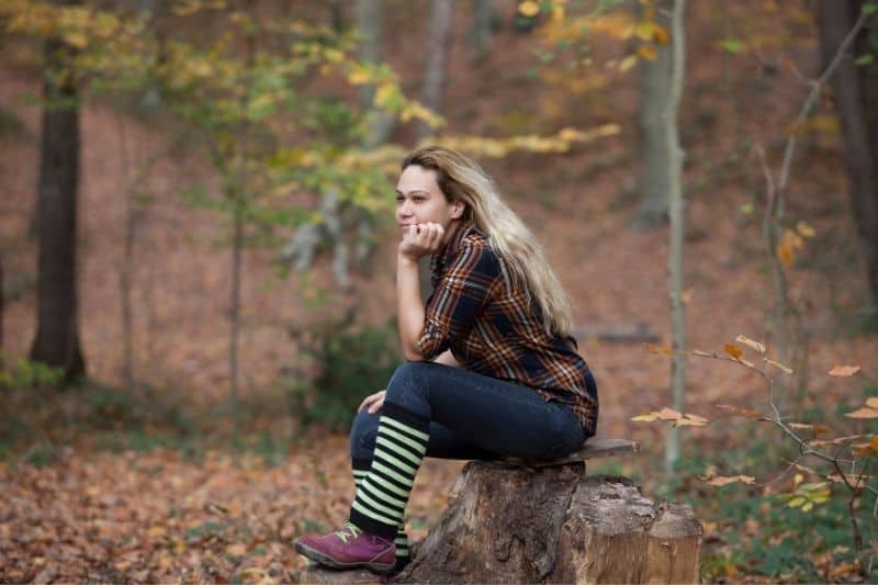 kvinna sitter på logga in skogen
