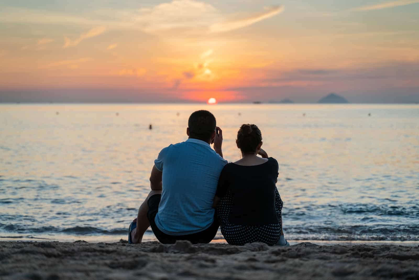man och kvinna sitter på stranden