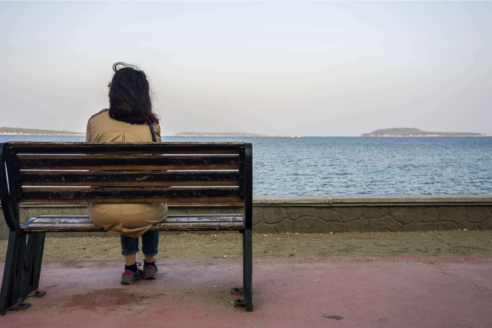 kvinna som sitter på bänken ensam