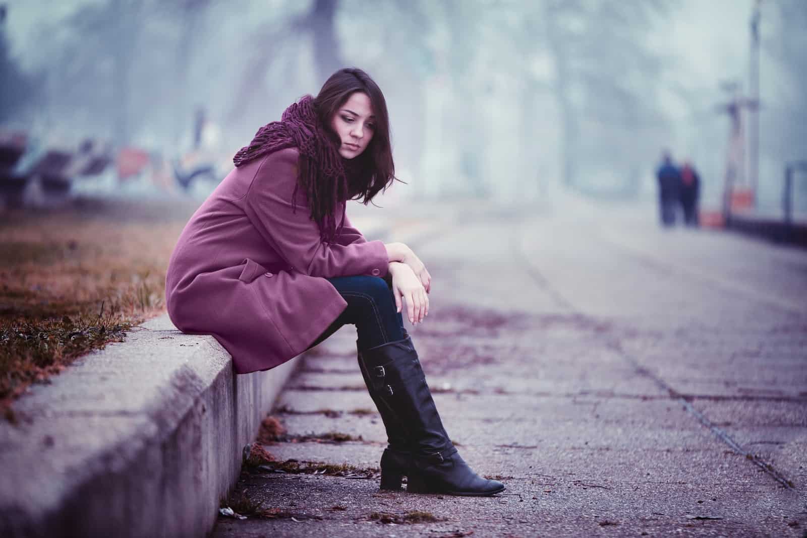 ledsen brunettkvinna som sitter ensam utomhus